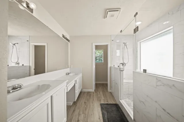 a bathroom with a double vanity sink and mirror with shower