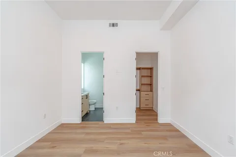 a view of an empty room with closet and wooden floor