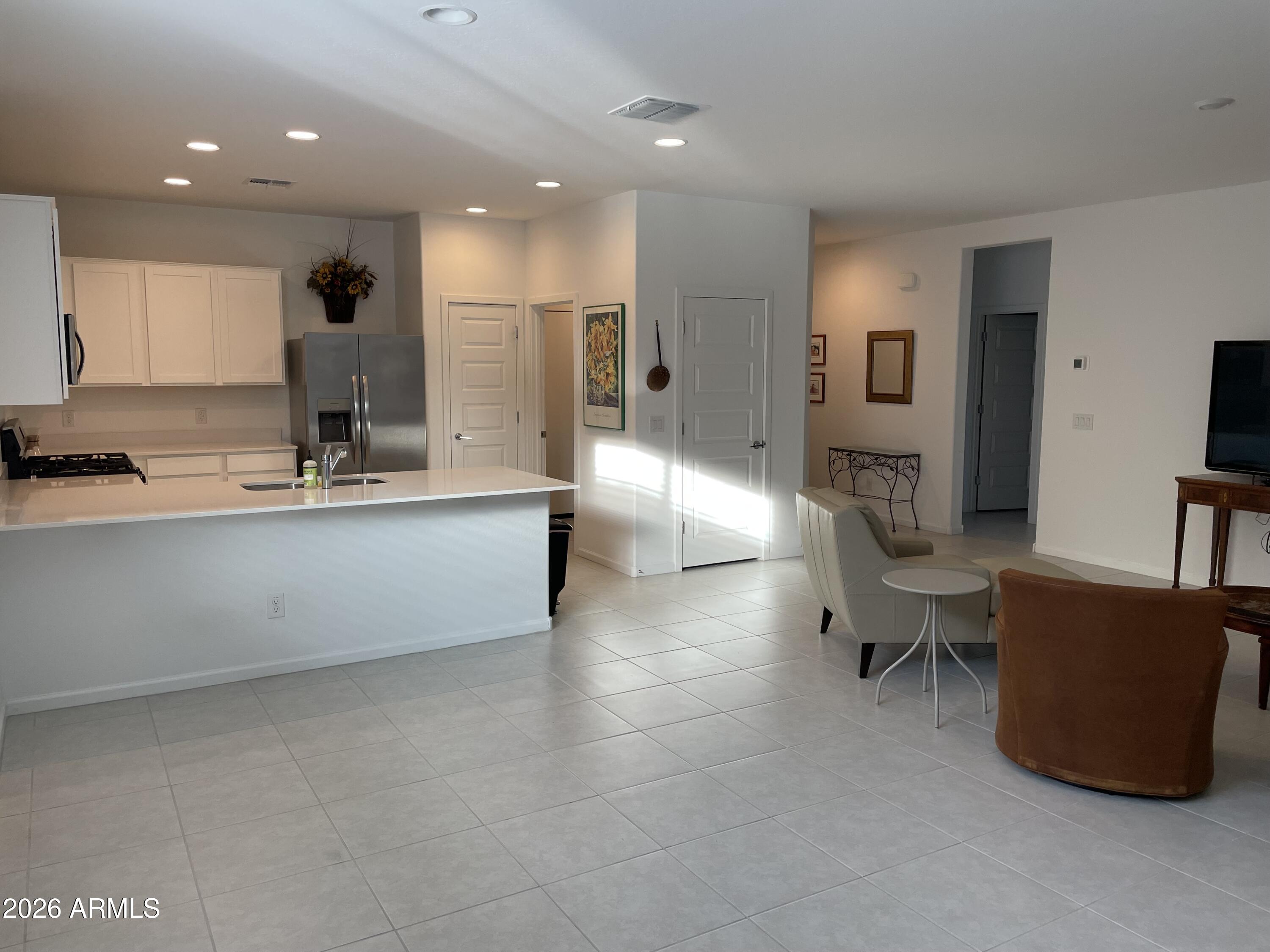 3009 East Riding Boot Way San Tan Valley, AZ 85140 - Photo 5 of 21 a large kitchen with stainless steel appliances a large counter top a couch and a view of living room