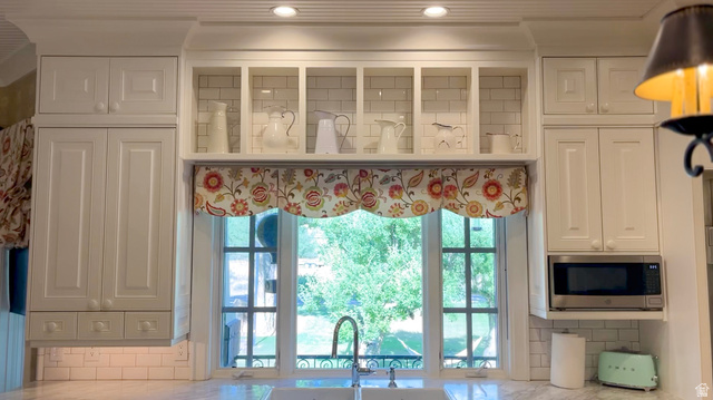 426 West Center Street Parowan, UT 84761 - Photo 21 of 107 White cabinetry with recessed panel doors, subway tile backsplash, and integrated shelving above a kitchen sink with a gooseneck faucet