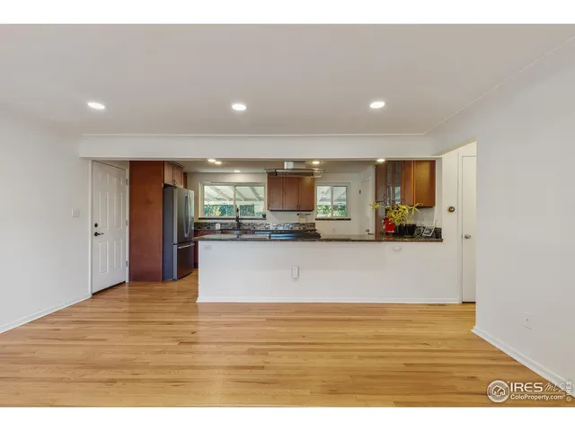 a view of kitchen and empty room with wooden floor