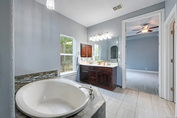 a en suite bathroom with a granite countertop sink a mirror and a bathtub
