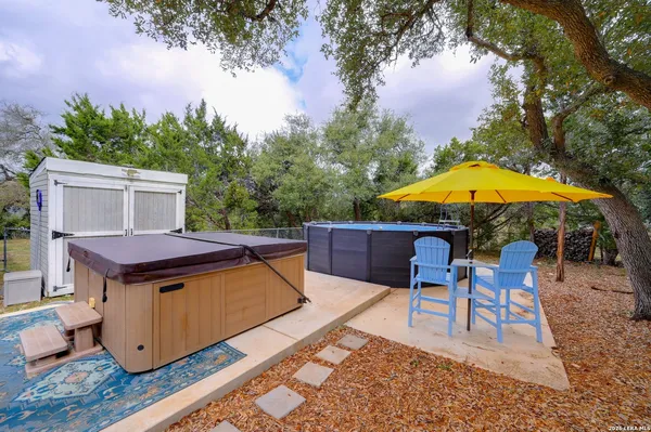 a backyard of a house with table and chairs under an umbrella