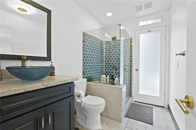 a bathroom with a granite countertop sink a toilet a mirror and shower