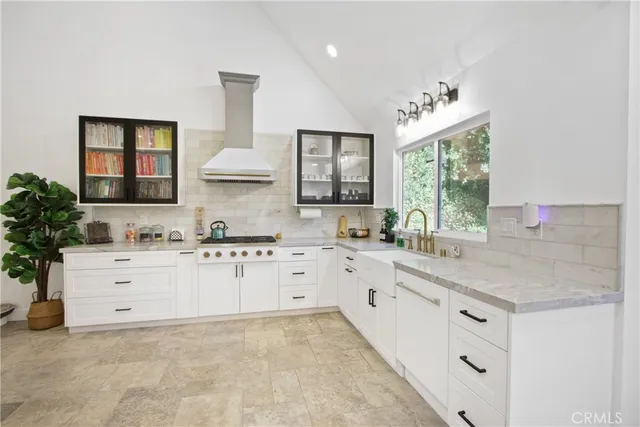 a kitchen with granite countertop a sink white cabinets and a large window