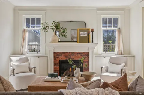 a living room with a fireplace and potted plants