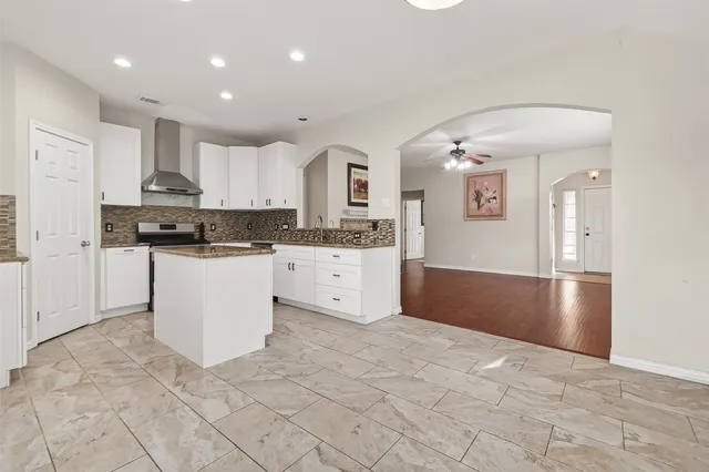 a kitchen with stainless steel appliances granite countertop a stove top oven a sink a refrigerator and white cabinets