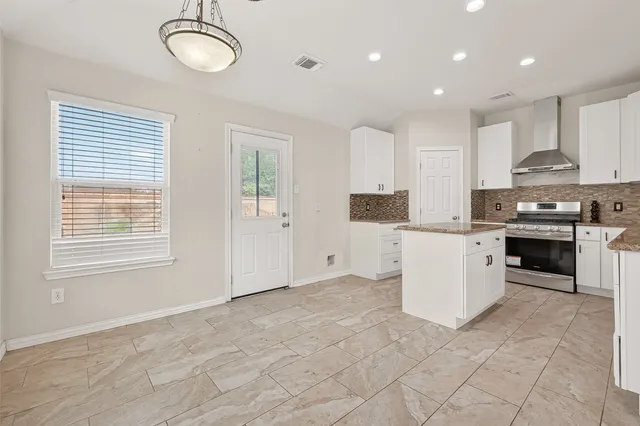 a kitchen with stainless steel appliances granite countertop a stove top oven a sink a refrigerator and white cabinets