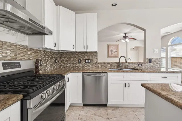 a kitchen with granite countertop a sink stove and cabinets