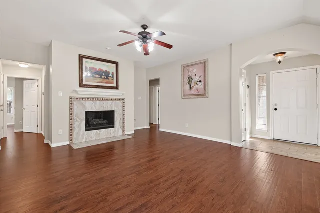 a view of an empty room with wooden floor and a fireplace