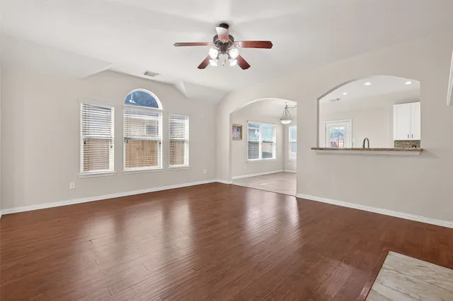 a view of an empty room with wooden floor and a window