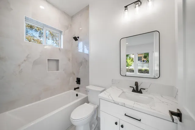 a bathroom with a toilet a sink a tub and mirror