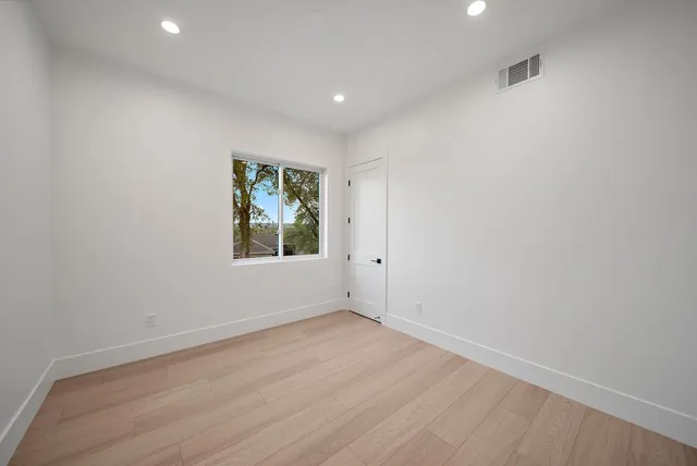an empty room with wooden floor and window