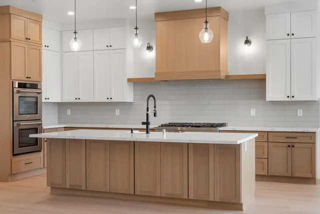 a kitchen with stainless steel appliances granite countertop a stove a sink and white cabinets