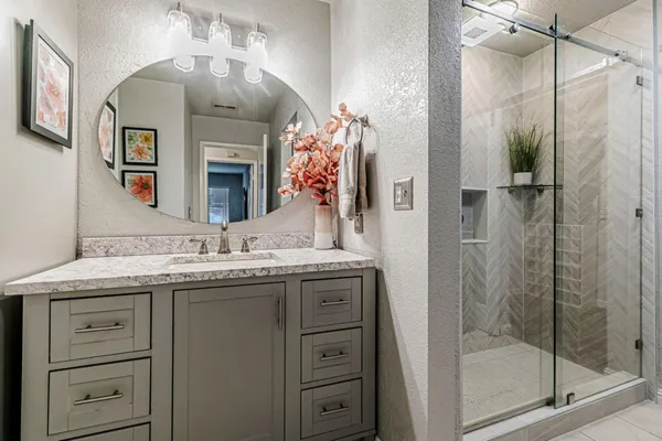 a bathroom with a granite countertop sink a mirror and a shower