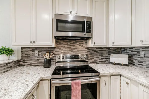 a kitchen with granite countertop a stove top oven microwave and cabinets