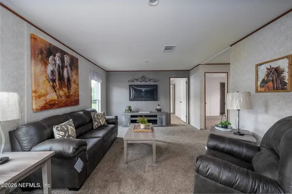 a living room with furniture a rug kitchen view and a table