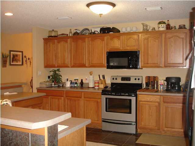 5127 Keyser Mill Road Baker, FL 32531 - Photo 8 of 13 a kitchen with stainless steel appliances a stove a sink a microwave and wooden cabinets