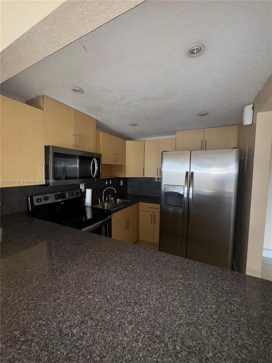 6095 West 19th Avenue, Unit 407 Hialeah, FL 33012 - Photo 3 of 10 a kitchen with stainless steel appliances a refrigerator and a counter top space