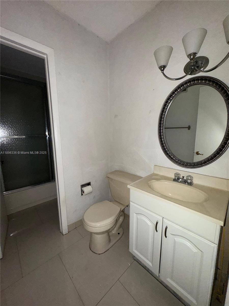 6095 West 19th Avenue, Unit 407 Hialeah, FL 33012 - Photo 6 of 10 a bathroom with a toilet sink and mirror