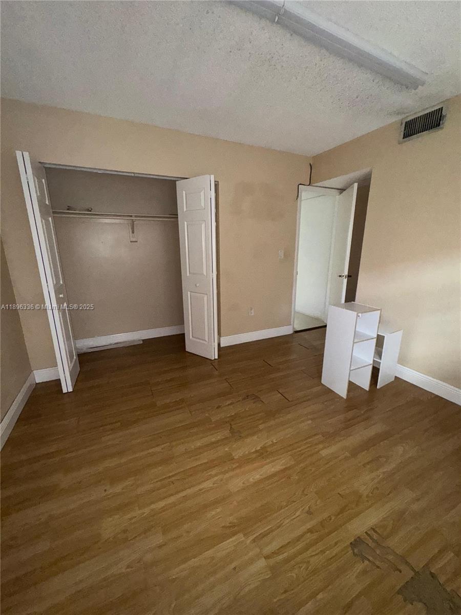6095 West 19th Avenue, Unit 407 Hialeah, FL 33012 - Photo 9 of 10 a view of an empty room with wooden floor and a window