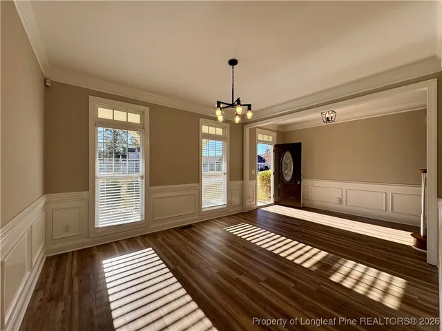 a view of an empty room with wooden floor and windows