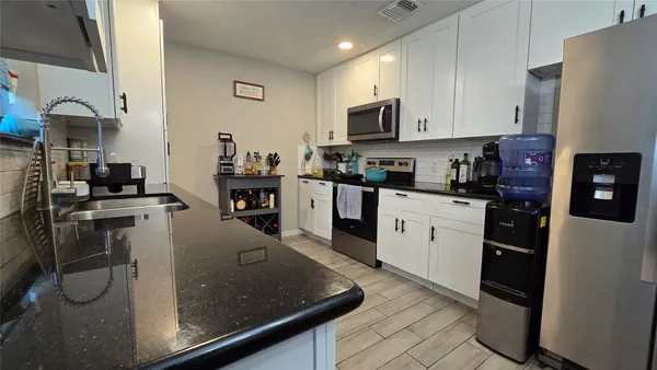 a kitchen with stainless steel appliances granite countertop a refrigerator sink and stove