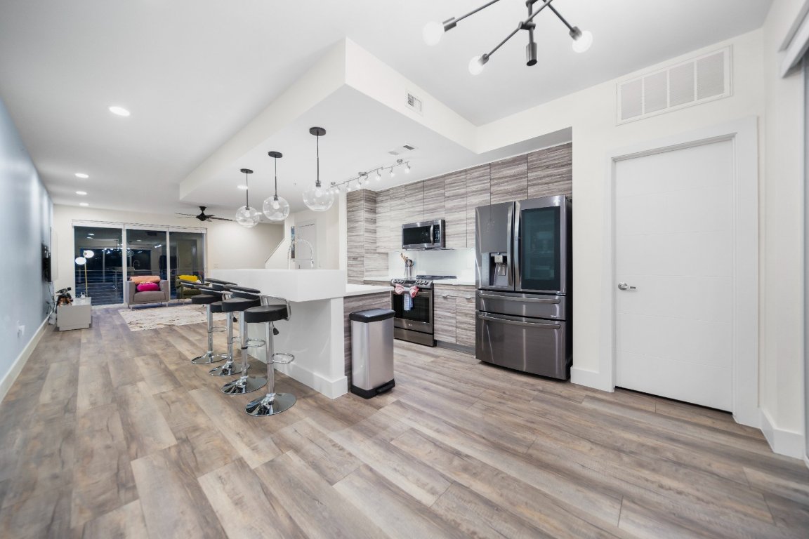 604 North Bluff Drive, Unit 247 Austin, TX 78745 - Photo 11 of 23 Kitchen featuring appliances with stainless steel finishes, modern cabinets, a breakfast bar area, light countertops, and a chandelier