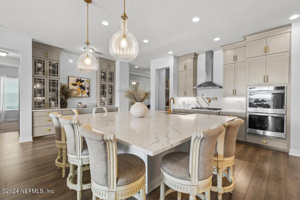 a kitchen with kitchen island granite countertop a dining table chairs and white cabinets
