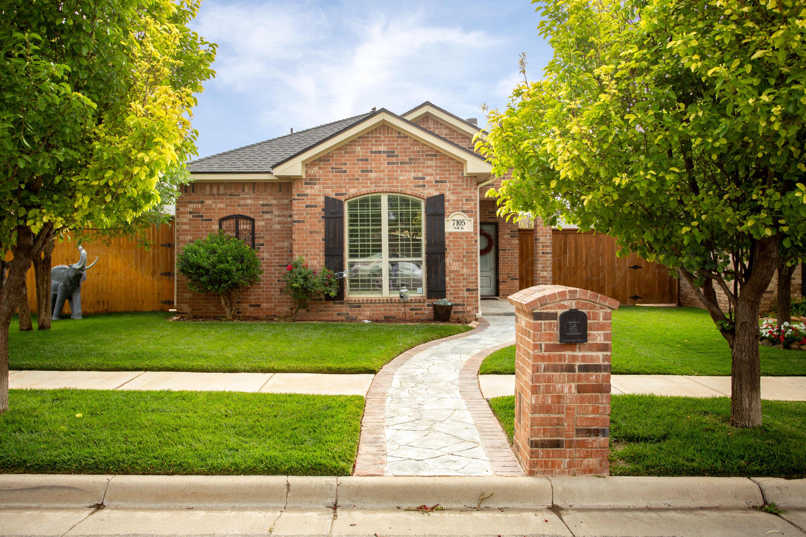 a front view of a house with a yard and trees