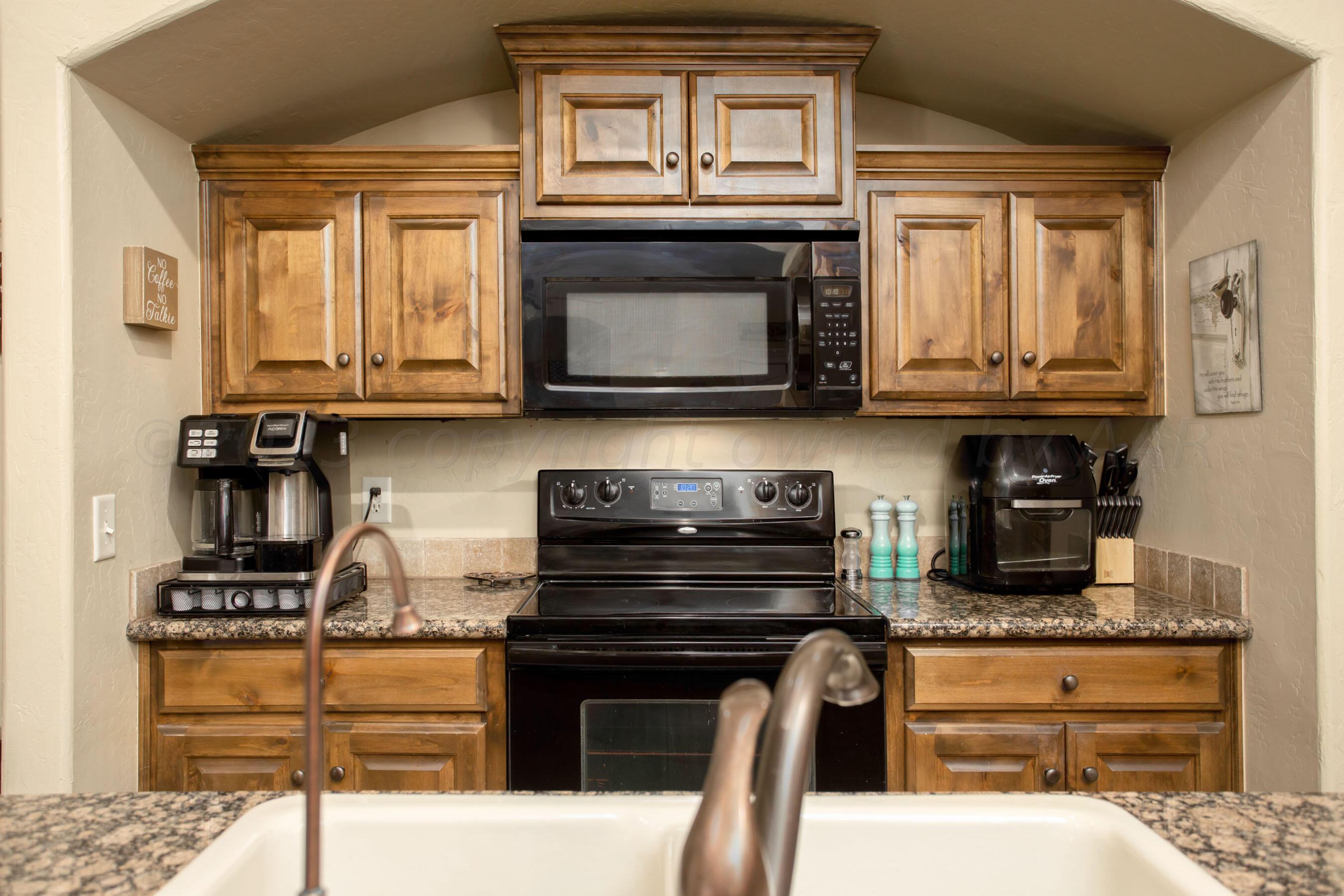 7105 Nick Street Amarillo, TX 79119 - Photo 8 of 24 a kitchen with granite countertop a stove and a microwave
