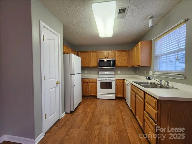 a kitchen with stainless steel appliances granite countertop a stove a sink dishwasher a refrigerator and a oven with wooden floor