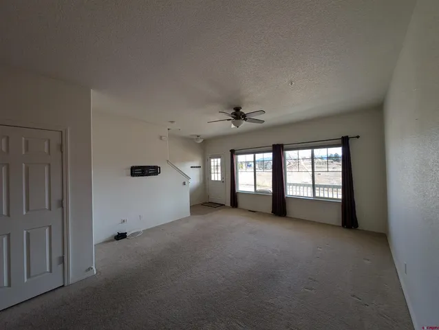 an empty room with windows and a ceiling fan