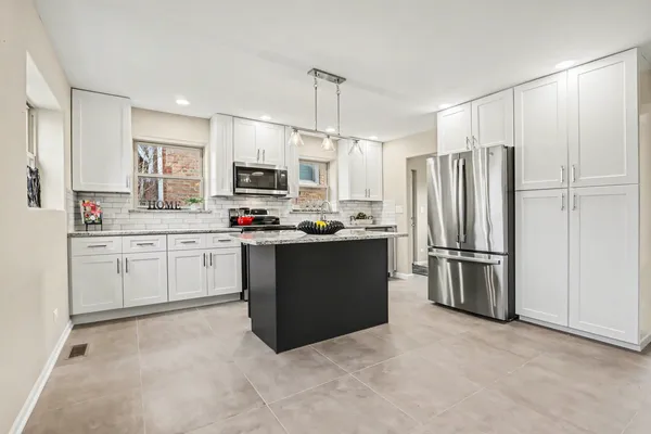 a kitchen with a refrigerator a sink and white cabinets