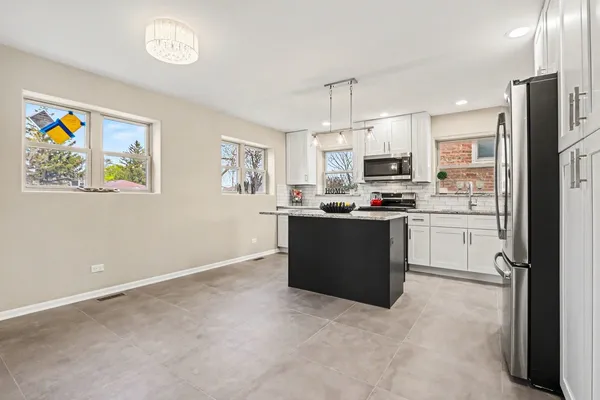a kitchen with stainless steel appliances kitchen island granite countertop a stove top oven a sink and a refrigerator