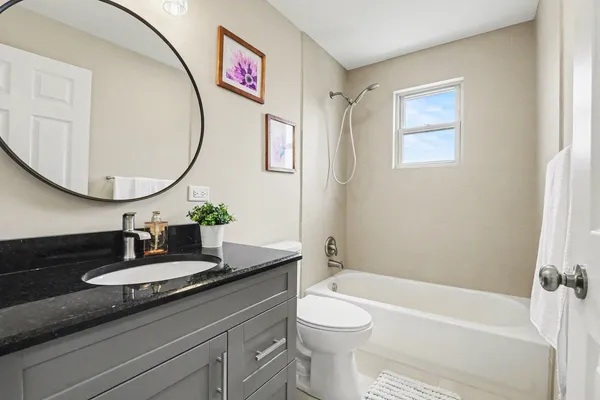 a bathroom with a granite countertop sink mirror vanity and toilet