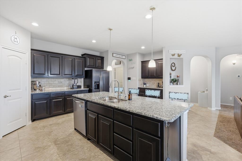 11500 Starlight Ranch Fort Worth, TX 76052 - Photo 14 of 40 Well-appointed kitchen featuring dark wood cabinetry, a large kitchen island with a granite countertop, and stainless steel appliances
