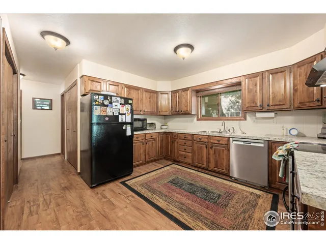 a kitchen with stainless steel appliances granite countertop a refrigerator a stove a sink a microwave and wooden cabinets