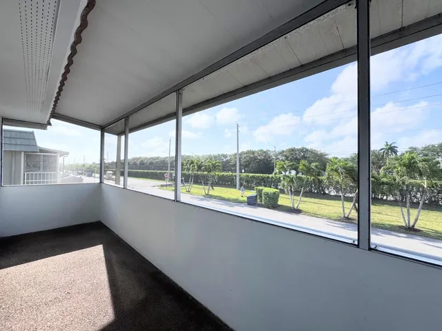 a view of an empty room with wooden floor and a large window