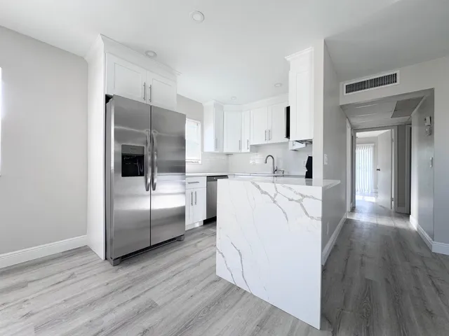 a kitchen with kitchen island white cabinets and stainless steel appliances