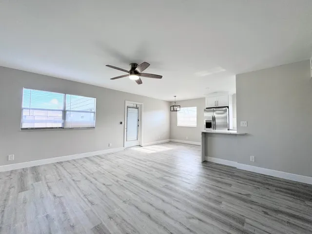 a view of empty room with wooden floor and fan