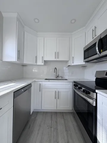 a kitchen with stainless steel appliances granite countertop a stove a sink and a microwave