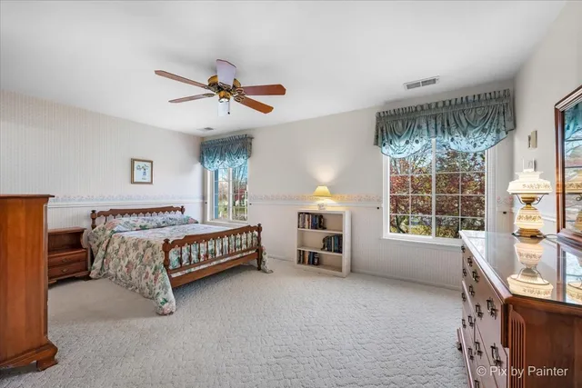 a spacious bedroom with a bed a dresser and windows