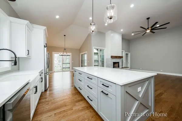 a large kitchen with kitchen island a stove a sink a center island and wooden floor