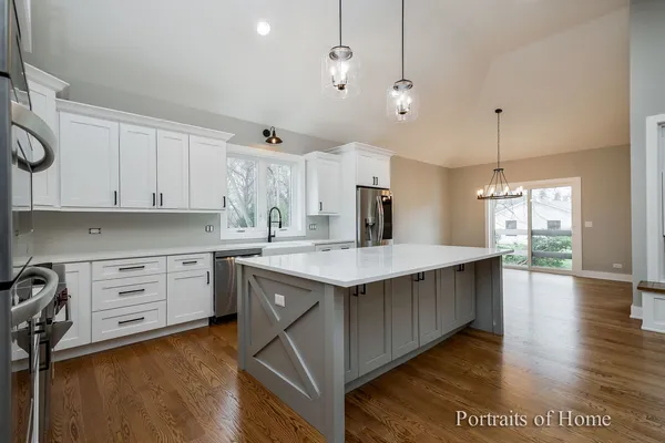 a kitchen with kitchen island granite countertop a stove a sink a center island and wooden floor