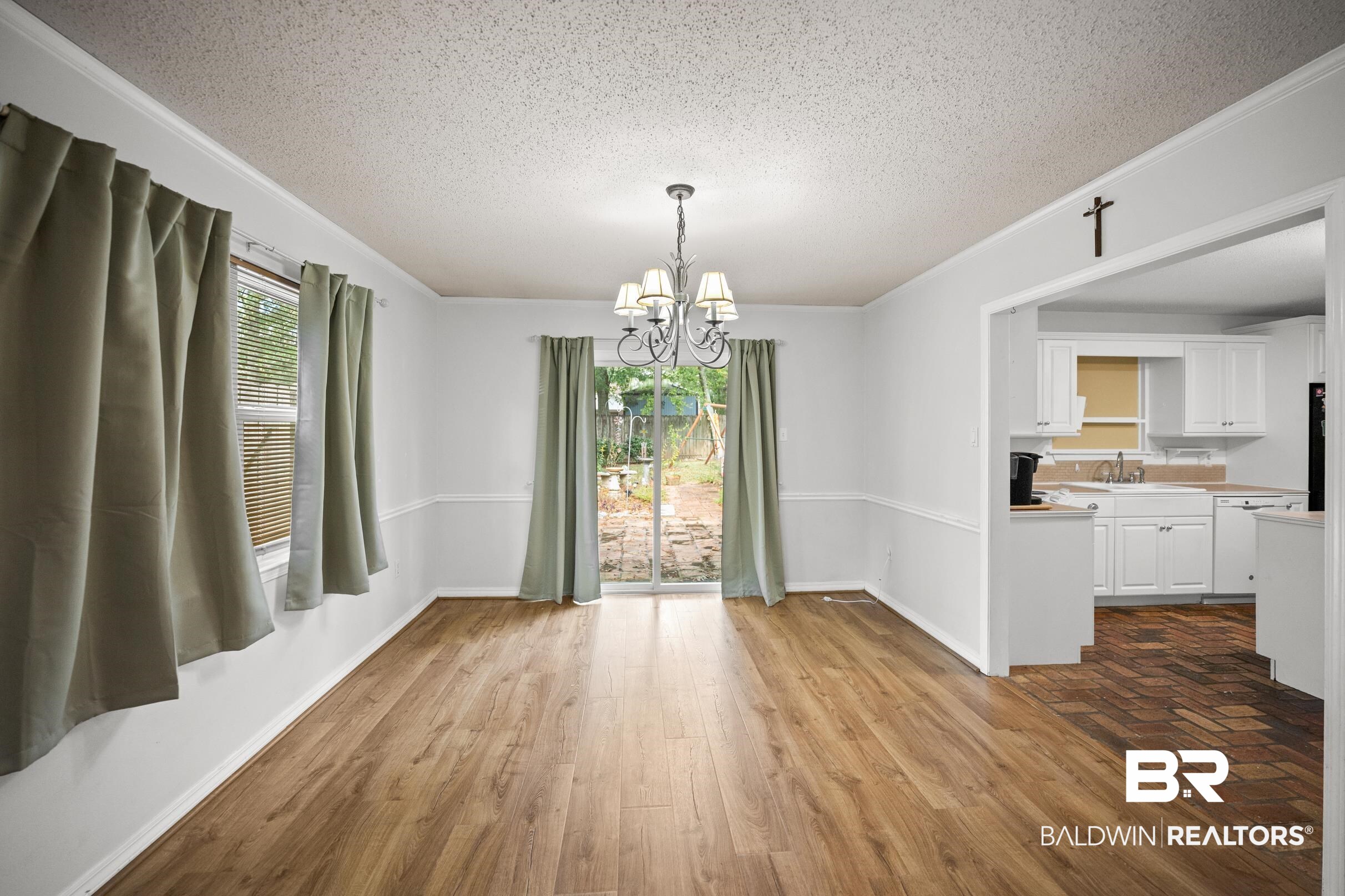 123 Dunbar Loop Daphne, AL 36526 - Photo 7 of 33 Unfurnished dining area featuring a chandelier, a textured ceiling, healthy amount of natural light, dark wood-style flooring, and ornamental molding