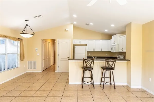 a kitchen with stainless steel appliances kitchen island granite countertop a refrigerator cabinets and chairs