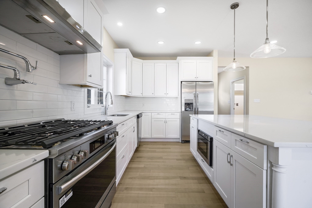 144 Bailey Street Fall River, MA 02724 - Photo 11 of 37 a kitchen with stainless steel appliances granite countertop a stove a sink dishwasher a refrigerator and white cabinets with wooden floor