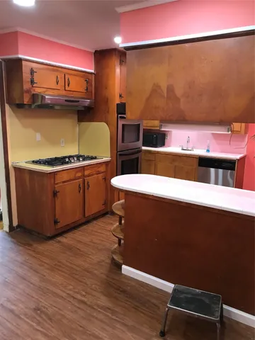 a kitchen with stainless steel appliances granite countertop a sink and wooden floor