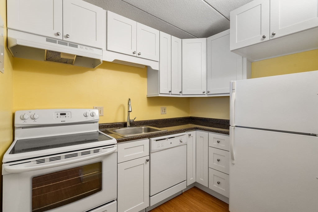 90 High Street, Unit 309 Dedham, MA 02026 - Photo 8 of 20 a kitchen with white cabinets and white appliances